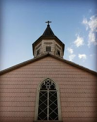 Low angle view of cross on building against sky