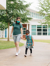 Side view of mother and daughter walking on street