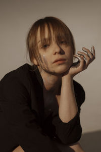 Portrait of woman sitting against wall at home