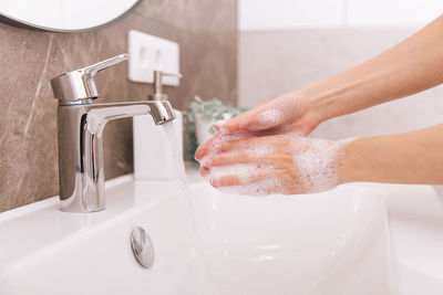 Cropped hand washing hands in sink