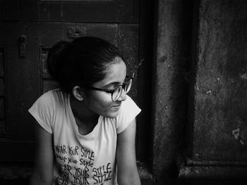 Woman wearing eyeglasses while looking away against wall