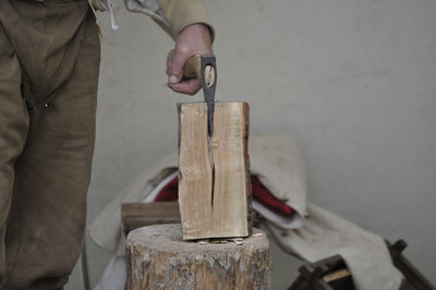 Midsection of carpenter cutting wood on tree stump