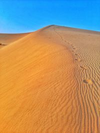 Sand dunes in desert against clear blue sky