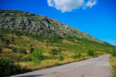 Road by mountain against blue sky