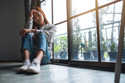 A sad and stressed young asian woman sitting alone in the room