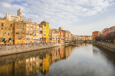 Buildings reflection in river canal against sky