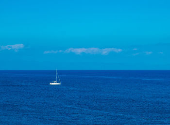 Boat sailing in sea against blue sky