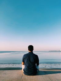 Rear view of man sitting on beach