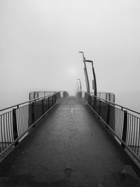 Footbridge over fog against sky