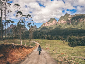 Rear view of woman walking on dirt road