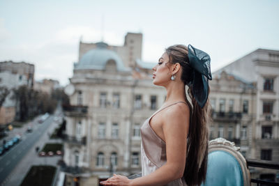 Side view of young woman standing against buildings in city