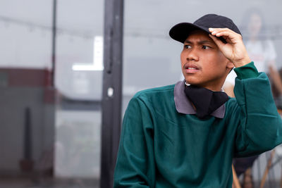 A photo of a handsome male model holding a black hat in a cafe