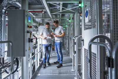 Two men in automatized high rack warehouse looking at tablet