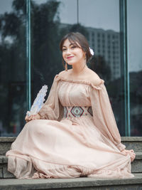 Beautiful woman in dress sitting against building