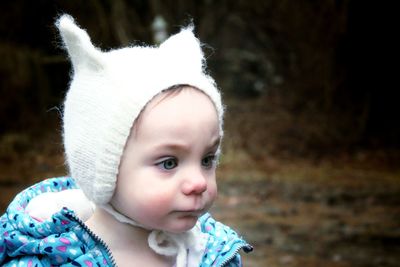 Close-up of cute baby girl in warm clothing looking away