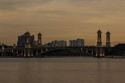 Bridge over river with buildings in background at sunset