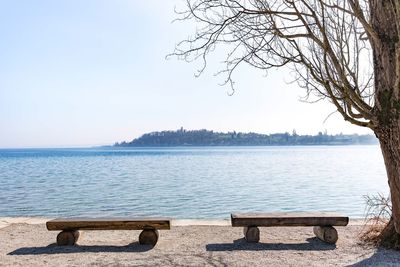 View of empty bench in front of calm blue sea