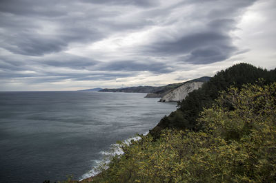 Scenic view of sea and mountains against cloudy sky