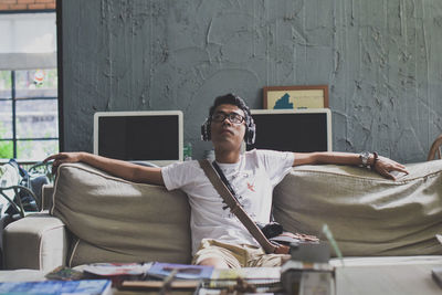 Young man relaxing on sofa in living room at home