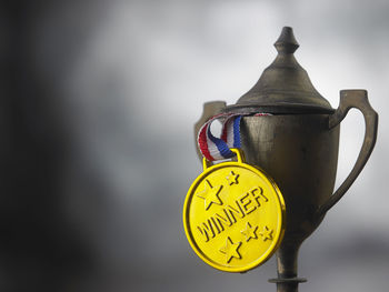 Close-up of rusty trophy and medal against sky