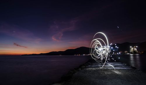 Light painting at riverbank against sky during dusk