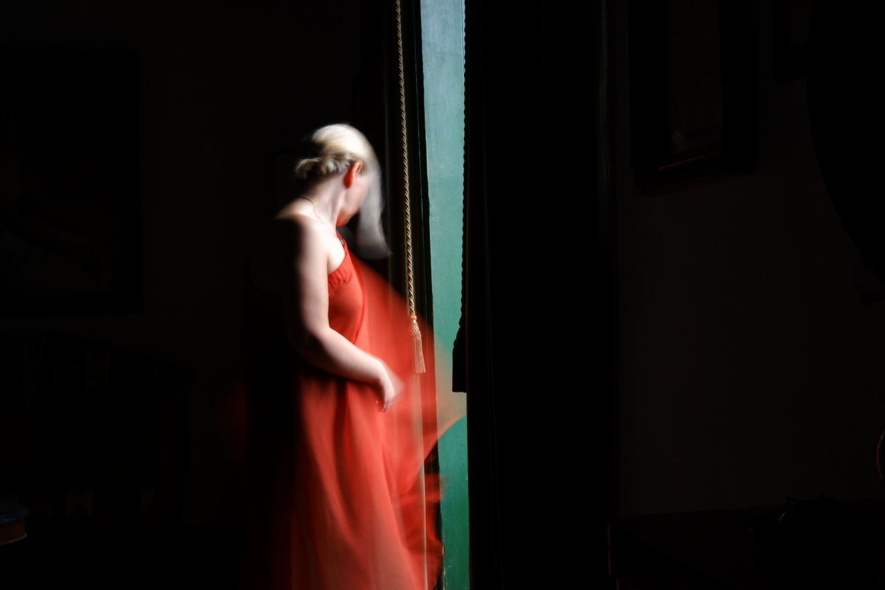 SIDE VIEW OF A YOUNG WOMAN LOOKING AWAY AT DARK