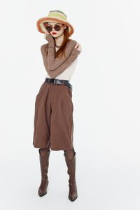 Portrait of woman wearing hat standing against white background