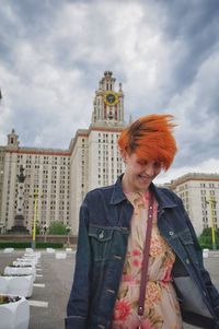 Woman standing against buildings in city against sky