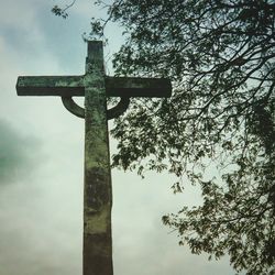 Low angle view of cross on tree against sky