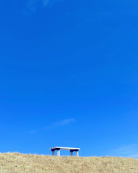 Lifeguard hut on field against clear blue sky