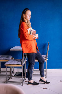 A young woman holds a stack of books. teaching a student according to textbooks.