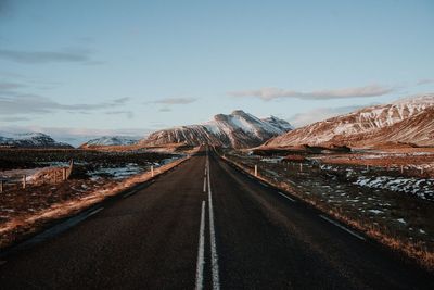 Empty road along landscape and mountains against sky