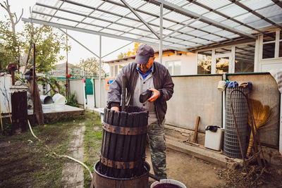 Portrait of a senior man disassembling a wine press.