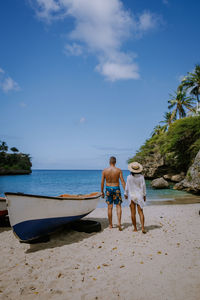 Rear view of men on beach against sky