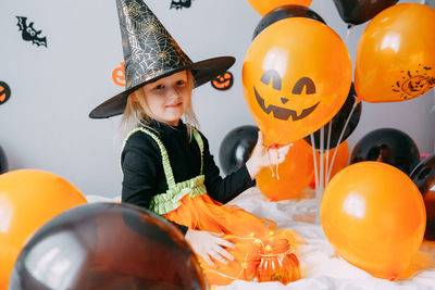 Children's halloween - a girl in a witch hat and a carnival costume with airy orange and black 