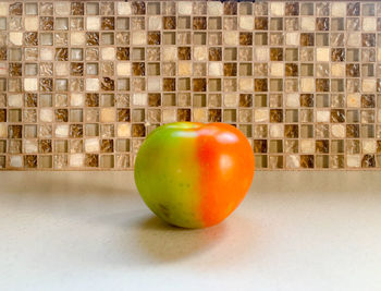 Close-up of apple on table against wall