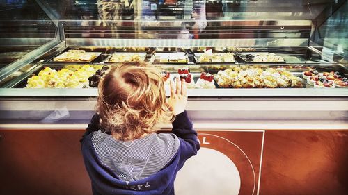 Rear view of boy standing at ice cream parlor