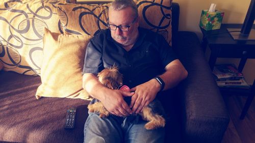 High angle view of man relaxing on sofa with dog at home