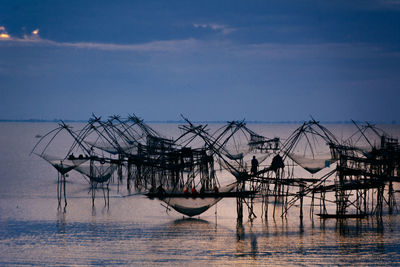 Fishing net in sea against sky during sunset