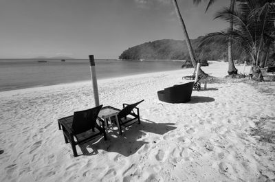 Chairs on beach by sea against sky