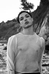 Young male with  androgynous look shot outdoor in black and white with rocks in background.
