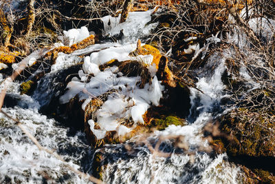 High angle view of stream flowing through rocks during winter