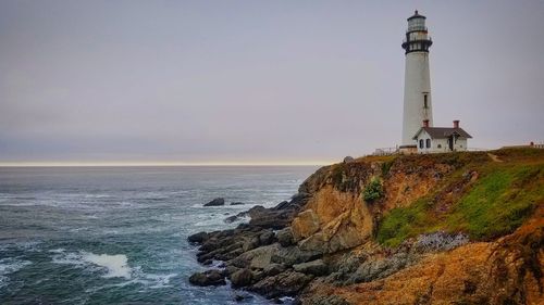 Lighthouse by sea against sky