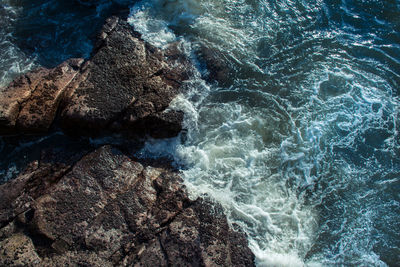 Directly above shot of waves splashing on rock formation in sea