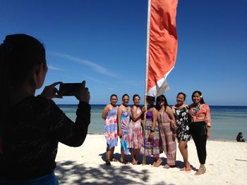 People photographing beach against clear sky