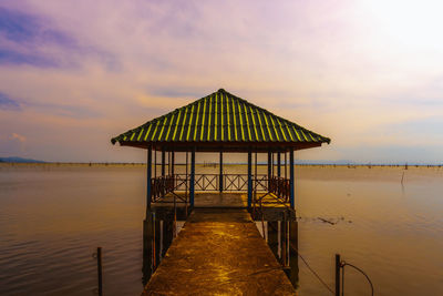 Gazebo on pier by sea against sky during sunset