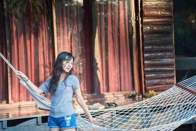 Young woman looking away standing by hammock