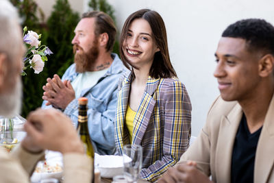 Portrait of smiling friends using mobile phone while sitting on table