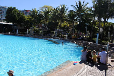 People swimming in pool against sky