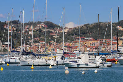 Sailboats moored in harbor against sky